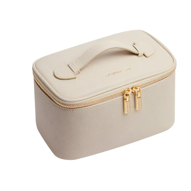 Astuccio portagioie in pelle beige con cerniera dorata e manico, design elegante e compatto, ideale per viaggi e organizzazione gioielli.