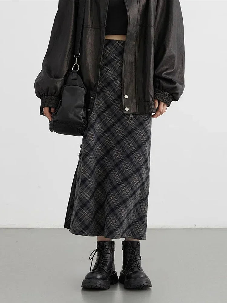 Gonna lunga a quadri grigi, giacca in pelle nera oversize, stivali neri robusti, borsa a tracolla nera. Moda streetwear autunnale donna.