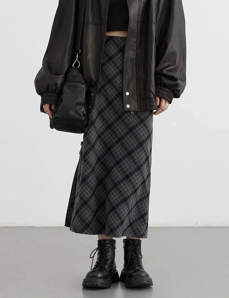 Gonna lunga a quadri grigi, giacca in pelle nera oversize, stivali neri robusti, borsa a tracolla nera. Moda streetwear autunnale donna.