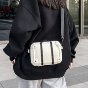 Zaino bianco rigido con cinghie nere indossato da una persona in abbigliamento casual. Design moderno, ideale per moda urbana e viaggi.