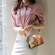 Donna con camicia rosa e gonna bianca indossa borsa a tracolla patchwork multicolore. Accessorio moda elegante, perfetto per look casual chic.