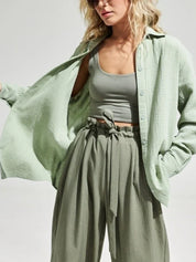 Donna con camicia verde chiaro in cotone, top corto e pantaloni a vita alta. Moda casual estiva, abbigliamento femminile trendy.