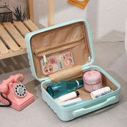 Valigia da viaggio aperta azzurra con prodotti cosmetici, telefono vintage rosa accanto. Organizzazione bagaglio, accessori viaggio, design retrò.