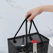 Borsa a rete nera con manici, contenente flaconi di cosmetici. Design elegante e pratico, ideale per organizzare prodotti da bagno.