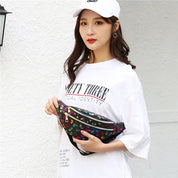 Giovane donna con cappellino bianco e maglietta oversize, indossa marsupio nero floreale. Moda casual, accessori trendy, street style femminile.