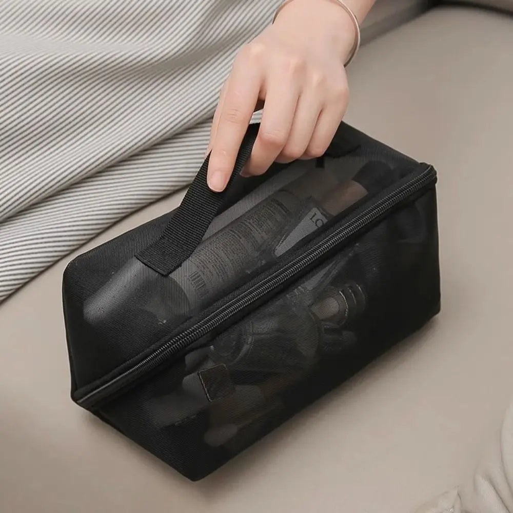Borsa da toilette nera trasparente con cerniera, manico superiore, contenente prodotti cosmetici. Ideale per viaggi, organizzazione trucco.