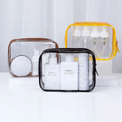 Tre borse trasparenti per cosmetici con flaconi e contenitori da viaggio, ideali per organizzare prodotti di bellezza. Design pratico e moderno.