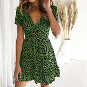 Abito verde leopardato da donna con scollo a V, maniche corte, sfondo bianco, decorazione pampas. Moda estiva elegante e casual.