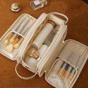 Borsa da trucco beige aperta con pennelli e flaconi cosmetici su sfondo marrone. Organizer da viaggio, accessori bellezza, cosmetici.