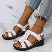 Sandali bianchi con zeppa, decorati con fiori, indossati con jeans strappati. Scarpe estive eleganti per donna, comode e alla moda.