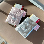 Due porta passaporti imbottiti, uno rosa e uno bianco, con biglietti aerei su sedile. Accessori da viaggio eleganti e funzionali.