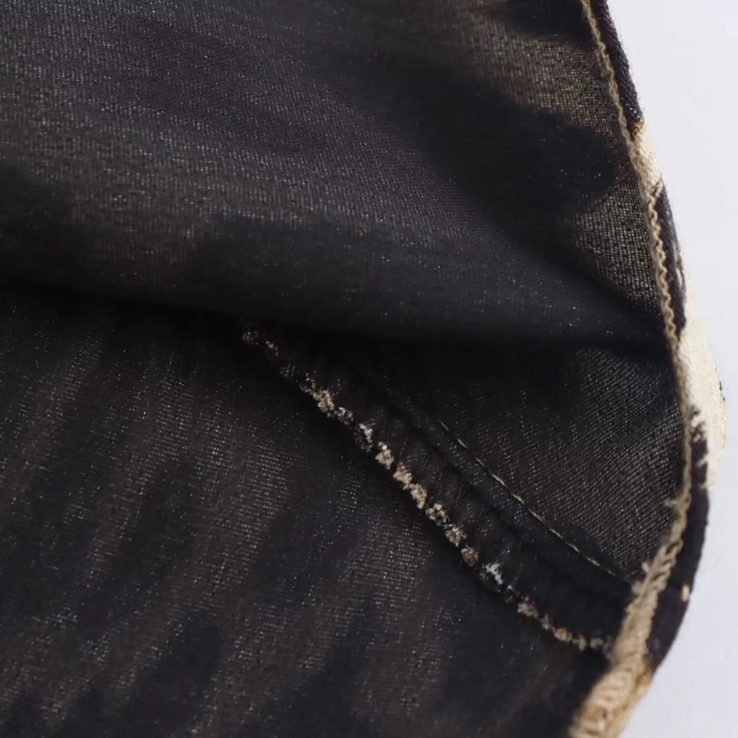 Cucitura dettaglio su tessuto nero, primo piano. Materiale di alta qualità, cucito resistente. Ideale per moda, abbigliamento, sartoria.