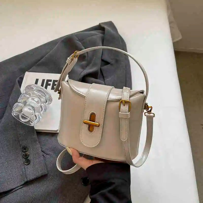 Borsa a tracolla beige elegante su giacca grigia, design moderno con chiusura dorata, perfetta per moda donna e accessori di tendenza.