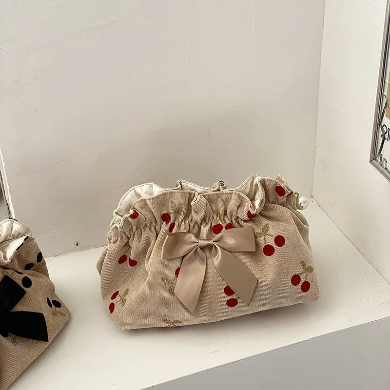 Borsa a sacchetto beige con fiocco e motivo ciliegie rosse, design elegante e femminile, perfetta per moda casual e accessori donna.