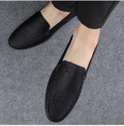 Scarpe mocassini uomo in pelle nera, eleganti e comode, su pavimento grigio. Ideali per look casual e formali. Scarpe da uomo di alta qualità.