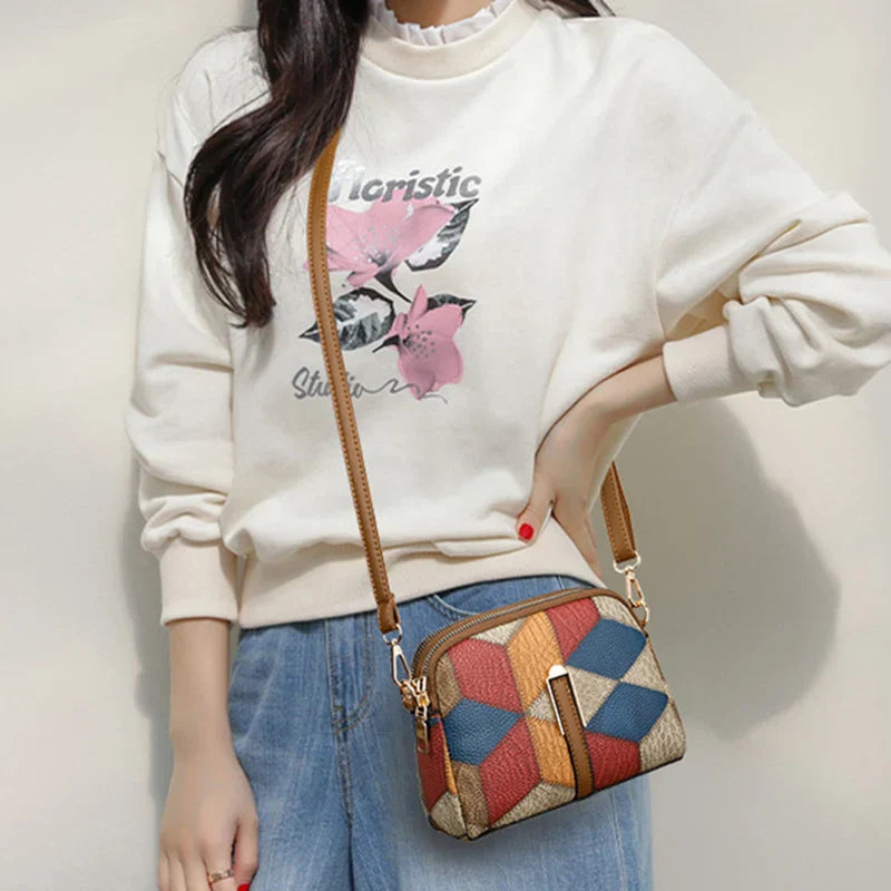 Borsa a tracolla multicolore con motivo geometrico, indossata da donna in maglione bianco e jeans. Accessorio moda casual, stile moderno.