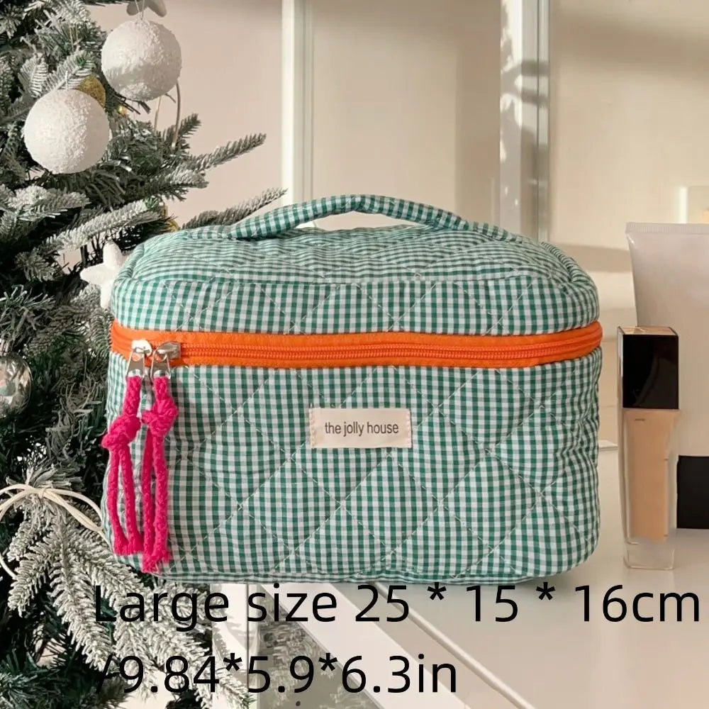 Borsa cosmetica verde a quadretti con cerniera arancione, dimensioni 25x15x16 cm, accanto ad albero di Natale. Organizer da viaggio elegante.