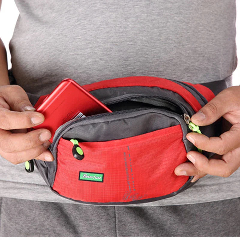 Marsupio sportivo rosso e grigio con cerniere verdi, indossato da una persona. Ideale per attività all'aperto, escursioni, viaggi. Tasche multiple.