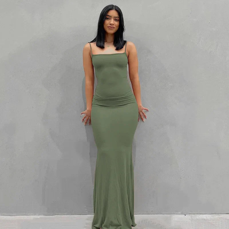 Abito lungo verde oliva aderente, senza maniche, indossato da una donna su sfondo grigio. Elegante moda femminile, stile minimalista.