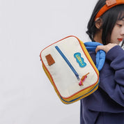 Zaino colorato per bambini con tasca frontale, cerniera blu e manico imbottito. Design moderno, ideale per scuola e tempo libero.