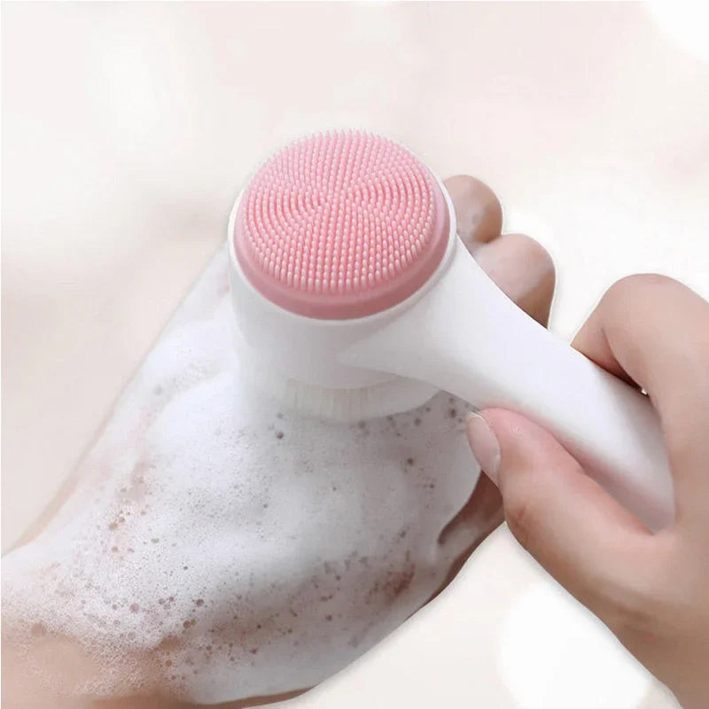 Spazzola per pulizia viso in silicone rosa, doppia azione, su mano con schiuma. Strumento esfoliante per cura della pelle, bellezza quotidiana.