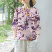 Donna con cappello indossa maglietta floreale viola e pantaloni bianchi, stile casual estivo. Moda donna, abbigliamento estivo, tendenza floreale.