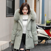 Giacca invernale donna con cappuccio in pelliccia sintetica grigia, abbinata a maglione bianco e jeans strappati. Moda casual autunno-inverno.