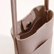 Borsa a tracolla in pelle rosa chiaro, design minimalista, chiusura a bottone, ideale per moda donna, accessorio elegante e versatile.