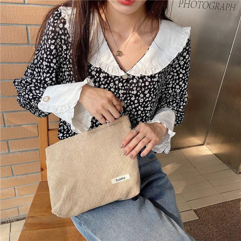 Donna con camicetta floreale bianca e nera, jeans, borsa a tracolla beige. Moda casual femminile, stile autunnale, accessori eleganti.