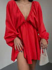 Donna con abito rosso a maniche lunghe e scollatura profonda, borsa di perle. Moda elegante, abbigliamento femminile trendy.
