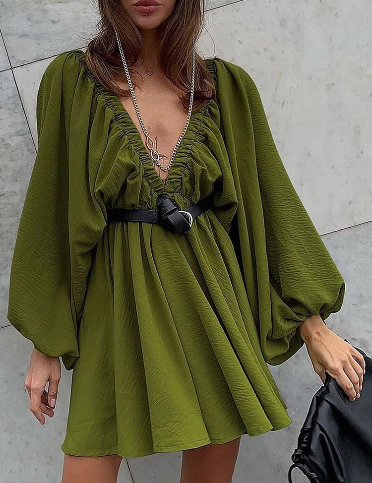 Abito corto verde oliva con maniche a sbuffo, scollo a V arricciato, cintura nera e collana lunga. Moda donna elegante e trendy.