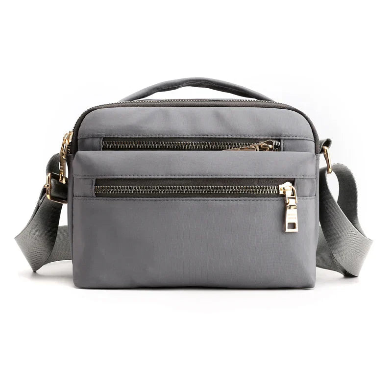 Borsa a tracolla grigia in nylon con doppia cerniera, tasche multiple e tracolla regolabile. Design elegante e funzionale per uomo e donna.