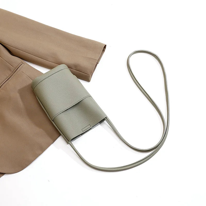 Borsa a tracolla verde oliva in pelle su giacca marrone, design minimalista, moda donna, accessorio elegante, tendenza 2023.