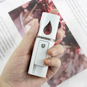 Nebulizzatore portatile bianco per viso, design elegante, tenuto in mano. Ideale per idratazione e cura della pelle. Accessorio beauty essenziale.