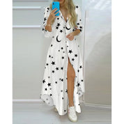 Abito lungo bianco con stampa stelle e lune nere, maniche lunghe, abbottonato, indossato con sneakers bianche. Moda donna casual elegante.