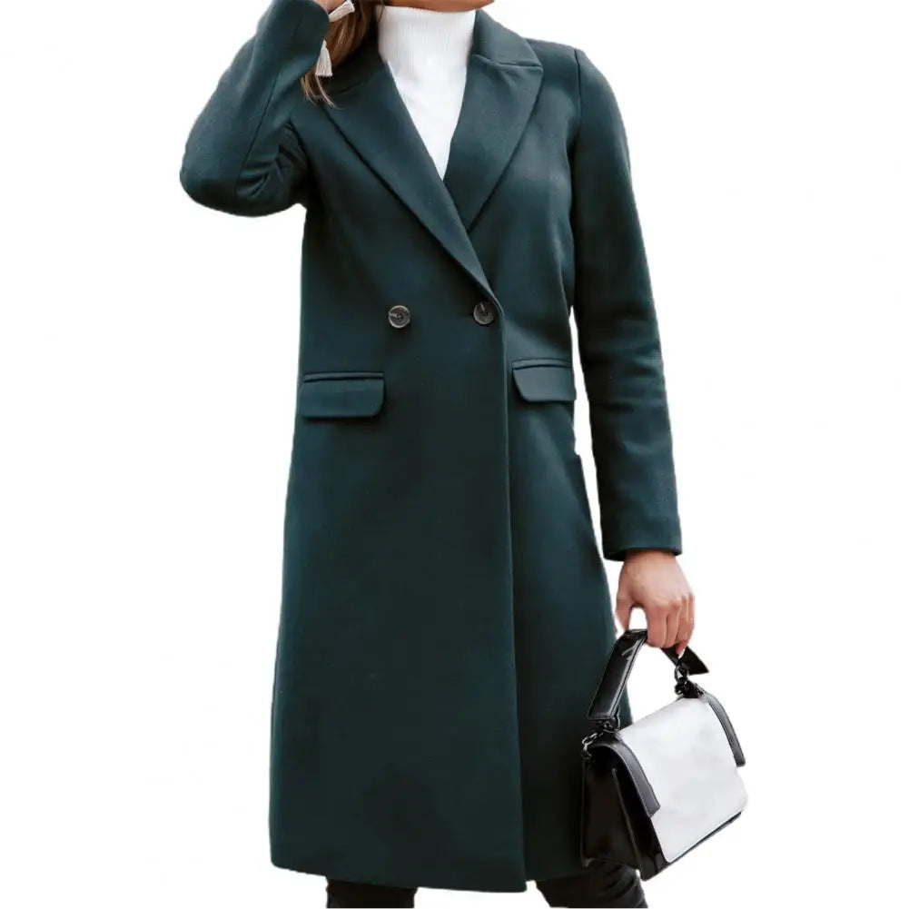 Cappotto lungo donna verde scuro elegante, doppio petto, con tasche, abbinato a borsa a mano bianca e nera. Moda autunno inverno.