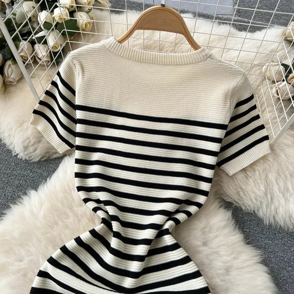 Maglione a righe bianche e nere su sfondo peloso, appeso su gruccia. Design casual, tessuto a coste, ideale per moda autunnale e invernale.