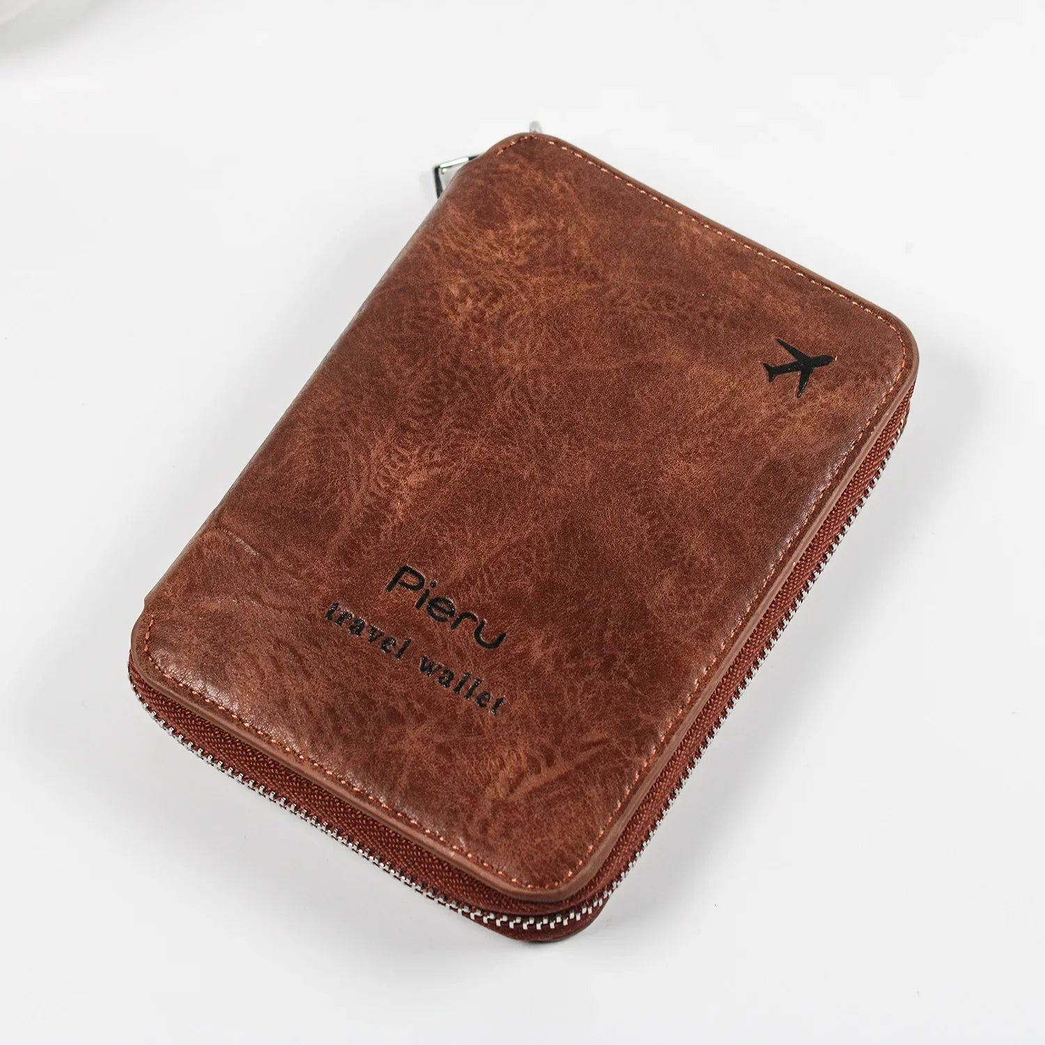 Portafoglio da viaggio in pelle marrone con cerniera, logo "Pieru" e icona aereo, ideale per documenti e carte. Accessorio elegante e funzionale.