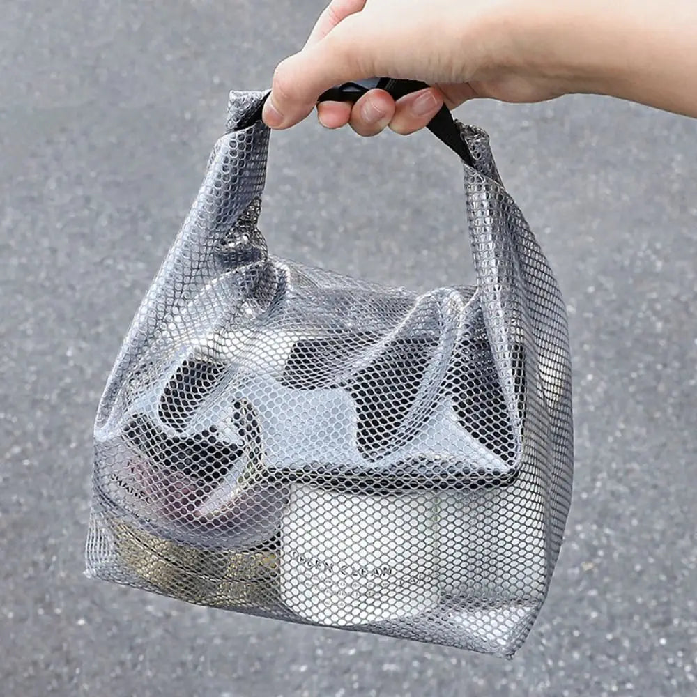 Borsa trasparente a rete con manico nero, contenente prodotti cosmetici. Design moderno, ideale per viaggi e organizzazione.