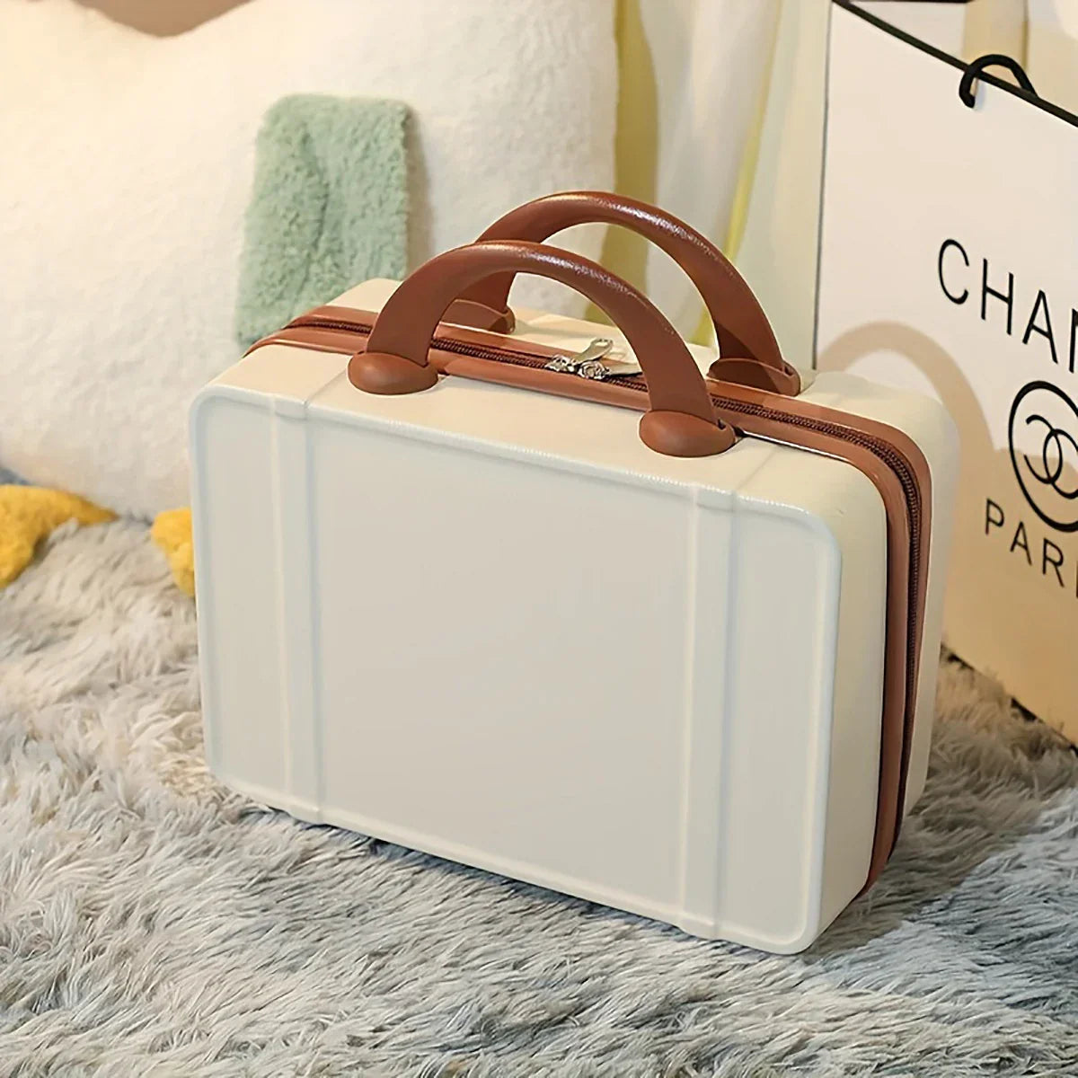 Valigia rigida beige con manici marroni su tappeto grigio, design elegante, ideale per viaggi, bagaglio a mano, stile moderno e compatto.