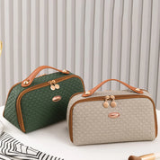 Due borse da viaggio eleganti in tessuto intrecciato, una verde e una beige, con manici in pelle marrone e dettagli dorati, su sfondo a righe.