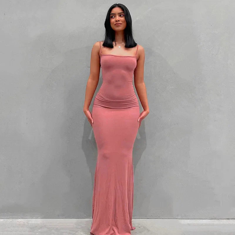Abito lungo rosa aderente, senza maniche, indossato da una donna su sfondo grigio. Moda elegante, abbigliamento femminile, stile moderno.