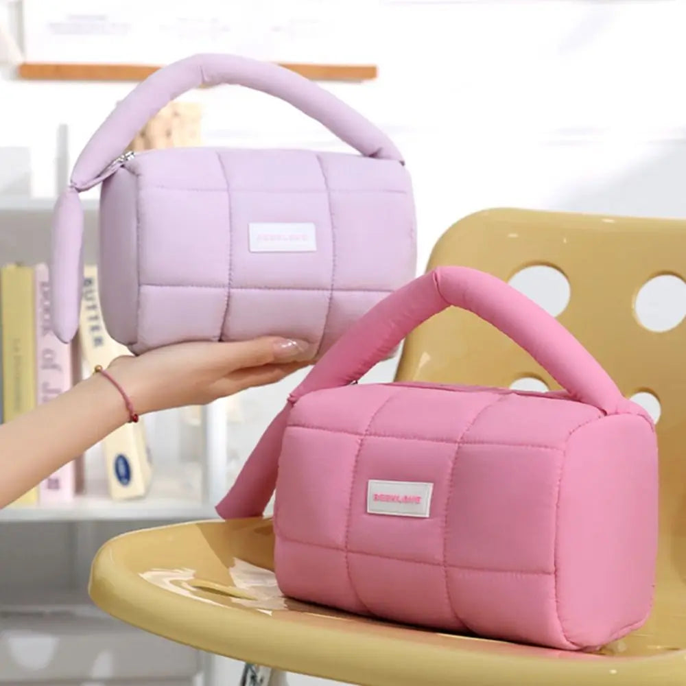 Due borse trapuntate in tessuto morbido, una rosa e una lilla, con manico imbottito, su sedia gialla. Design moderno, moda femminile, accessori eleganti.