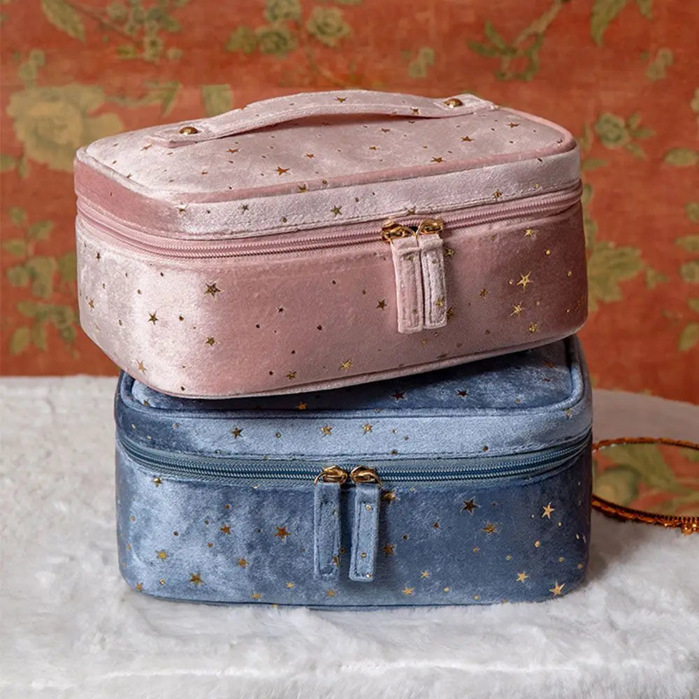 Due astucci in velluto, uno rosa e uno blu, con motivi a stelle dorate, su sfondo floreale. Eleganti e ideali per cosmetici o accessori.