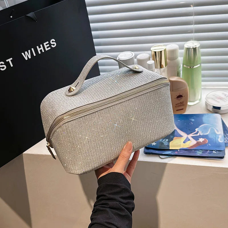 Borsa cosmetica glitterata argento con manico, davanti a prodotti di bellezza su uno sfondo di scatola nera e finestra con persiane.
