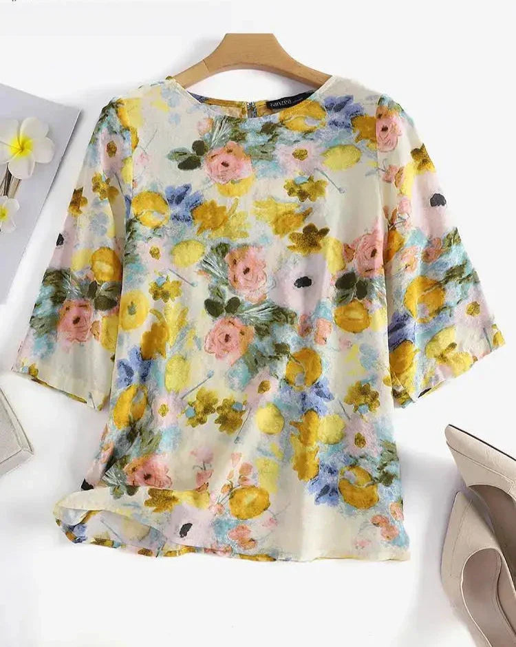 Blusa floreale donna in chiffon, maniche a tre quarti, colori pastello, sfondo bianco. Elegante e leggera, perfetta per la primavera.