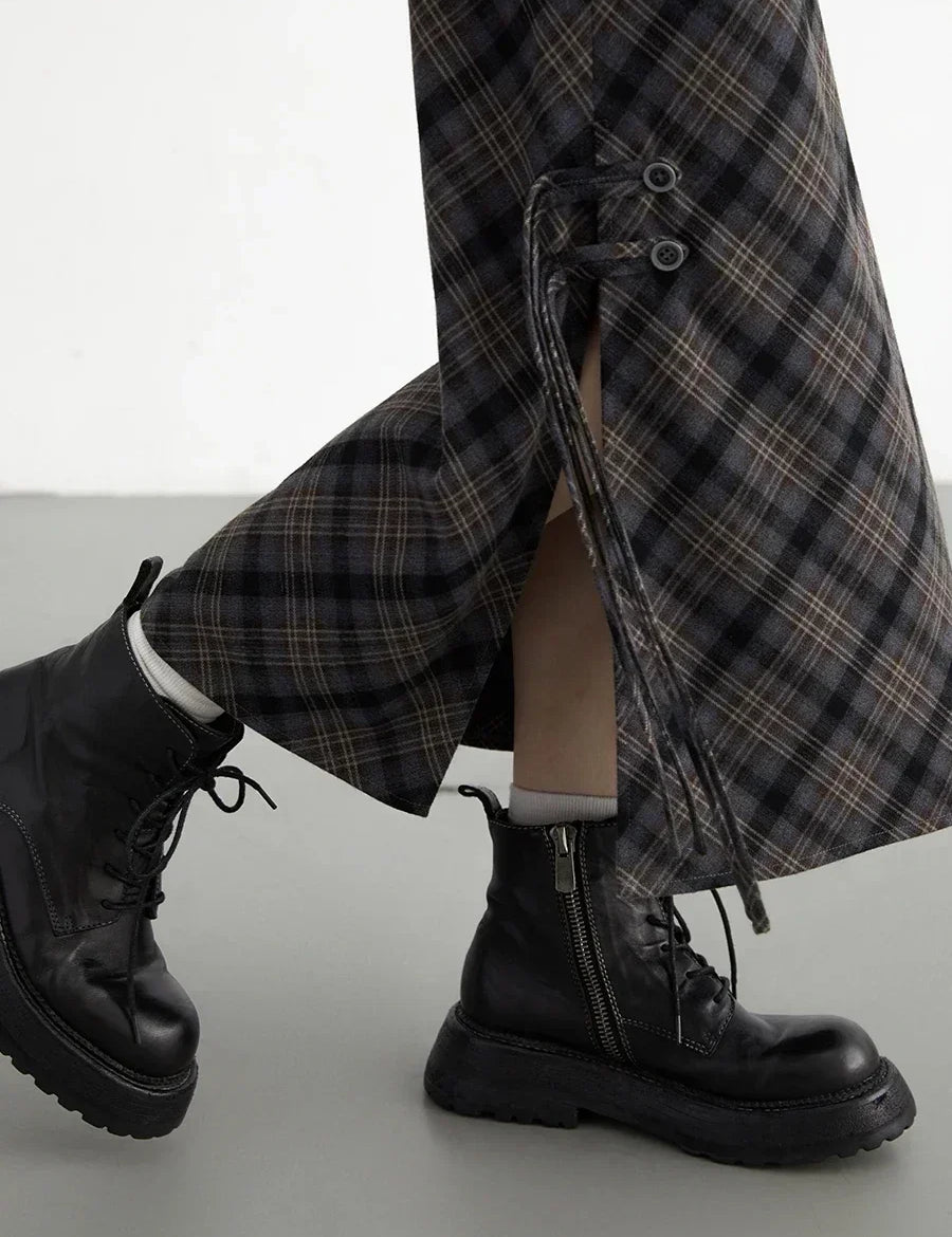 Pantaloni a quadri con lacci laterali, abbinati a stivali neri in pelle con cerniera. Moda autunnale, stile casual chic.