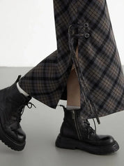 Pantaloni a quadri con lacci laterali, abbinati a stivali neri in pelle con cerniera. Moda autunnale, stile casual chic.
