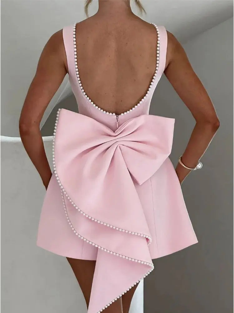 Abito rosa elegante con fiocco grande e perline, scollatura profonda sulla schiena, design moderno, perfetto per eventi formali e cerimonie.