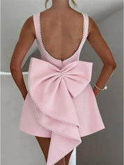 Abito rosa elegante con fiocco grande e perline, scollatura profonda sulla schiena, design moderno, perfetto per eventi formali e cerimonie.